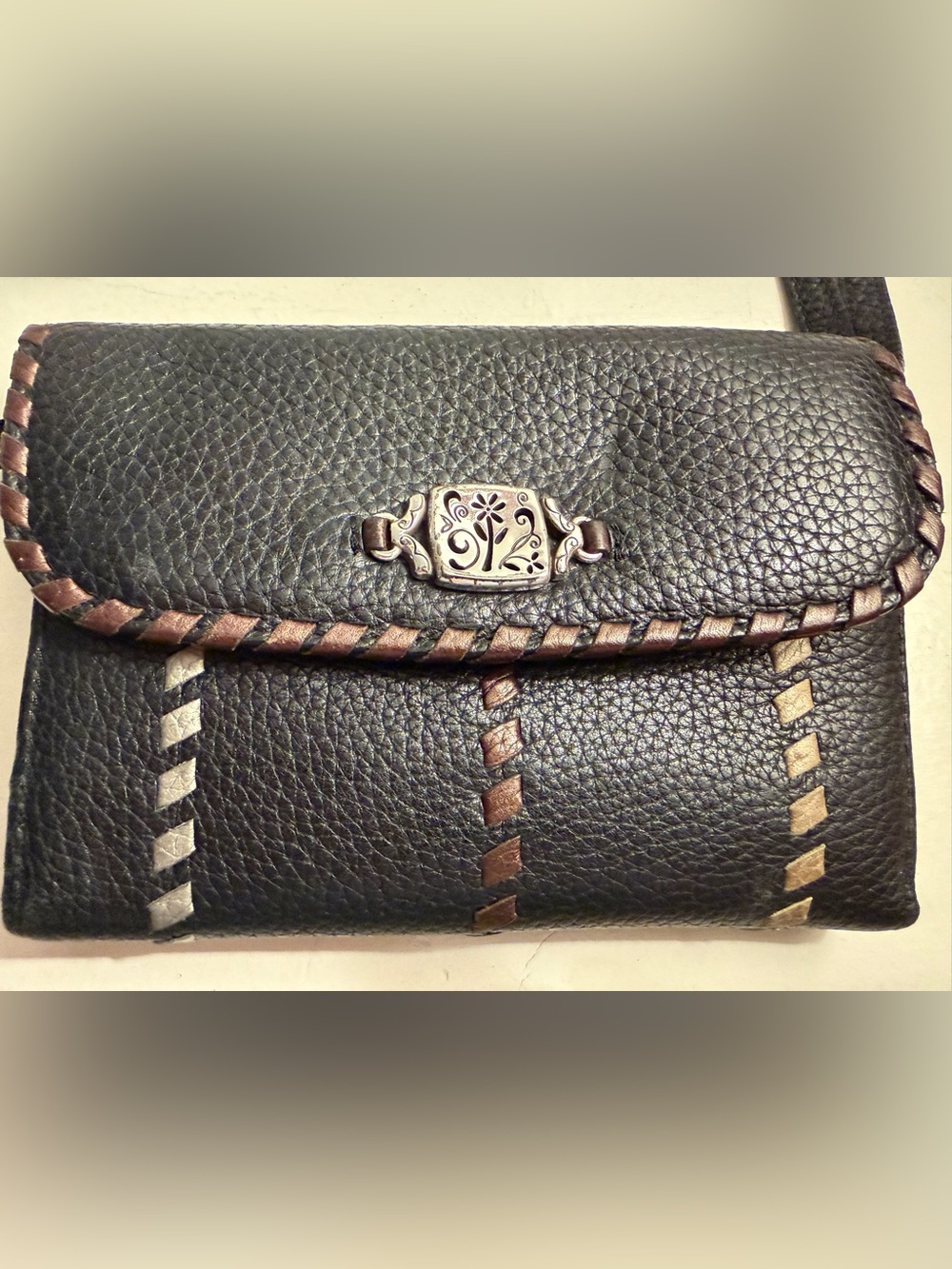 Brighton leather wallet/crossbody with whipstitching and filigree ornament.